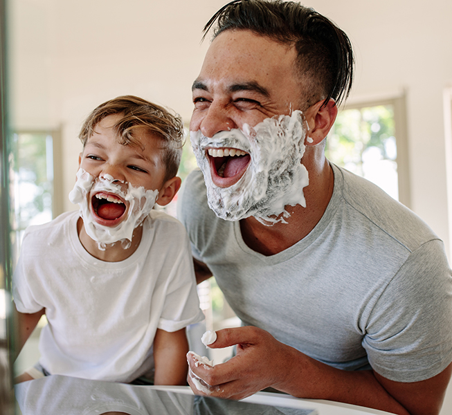 Father and son with shaving cream beards and laughing