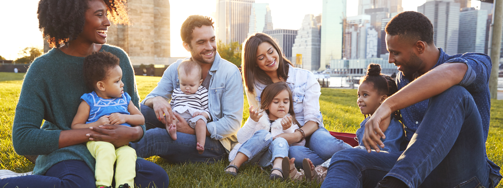 parents and children sitting on lawn talking with each other and laughing