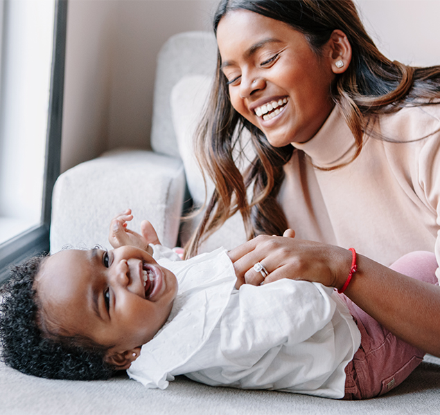 parent tickling and laughing with their baby